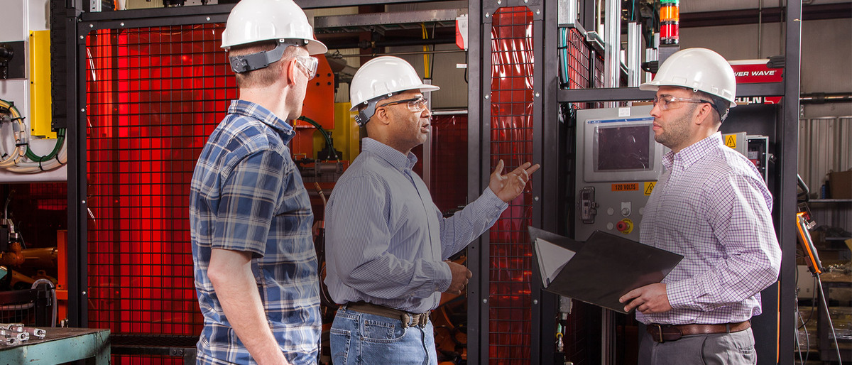 Three men in hard hats having a conversation