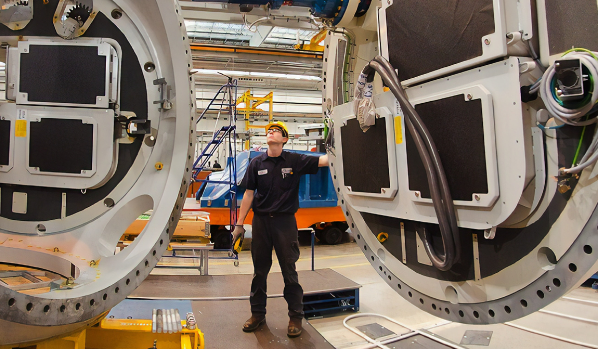 Man connecting two large machine pieces. 